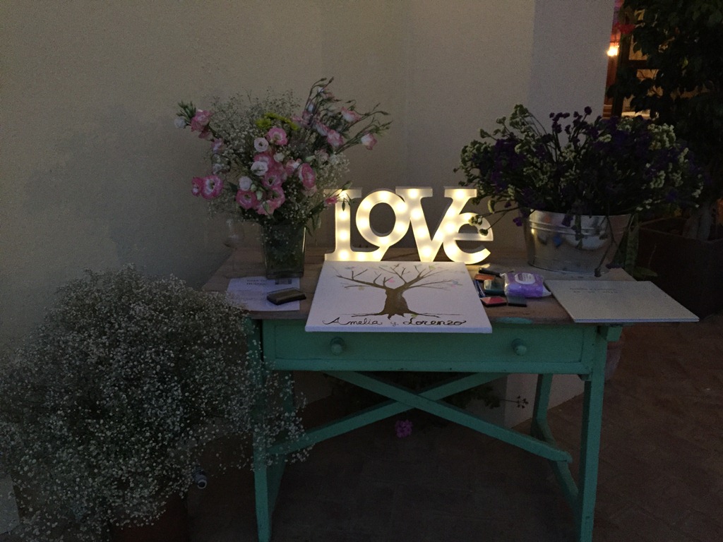 Mesa de firmas con letras iluminadas y centros de flores en Dehesa Bolaños