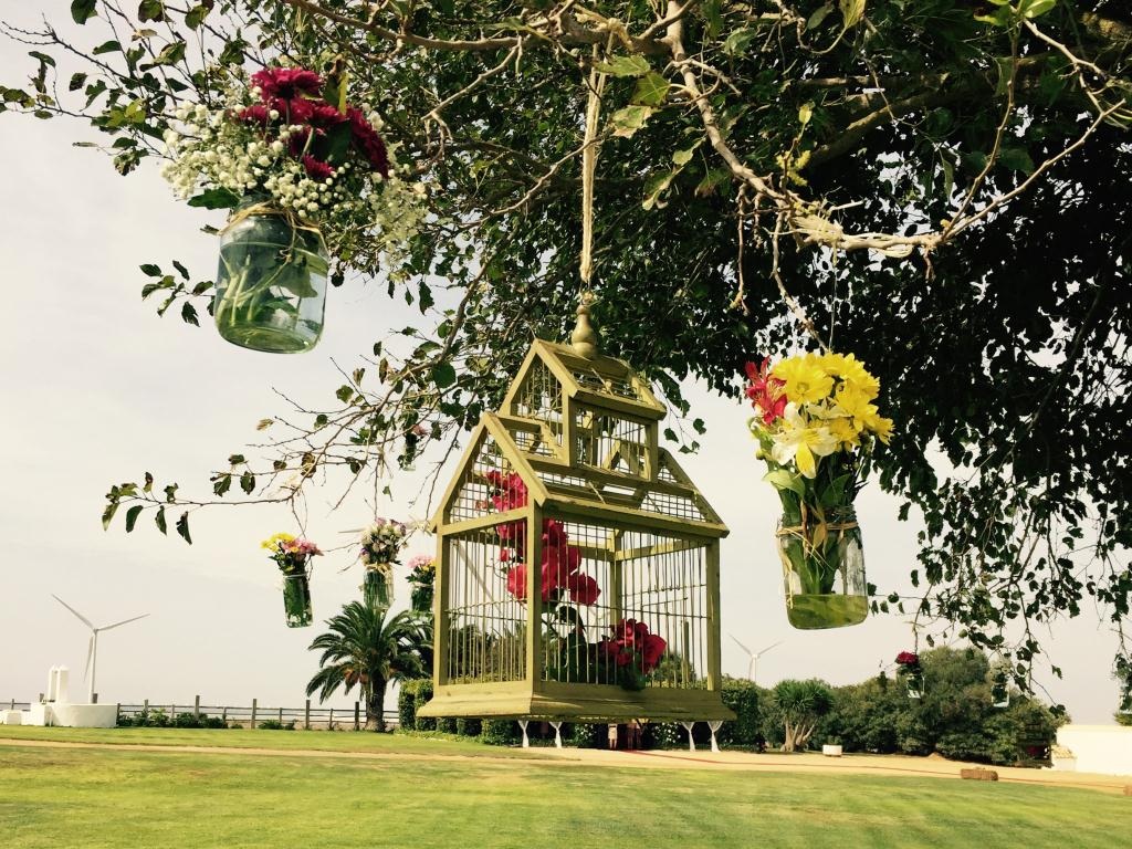 Jardines desde árbol con jaulas y tarros de flores en Dehesa Bolaños